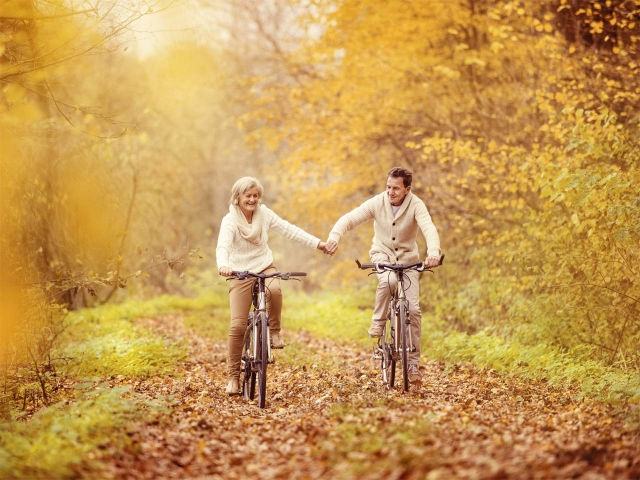 Parella senior passejant en bicicleta tardor